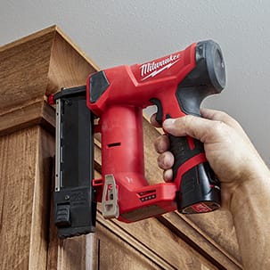 Compact cordless 23 gauge pin nailer being used to finish cabinet case.