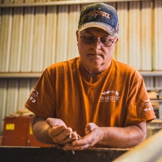 Traeger pellet mill worker checking quality of pellets. Traeger pellet mill worker checking quality of pellets.