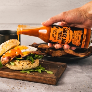 Traeger Original Hot Sauce pouring onto a breakfast sandwich.