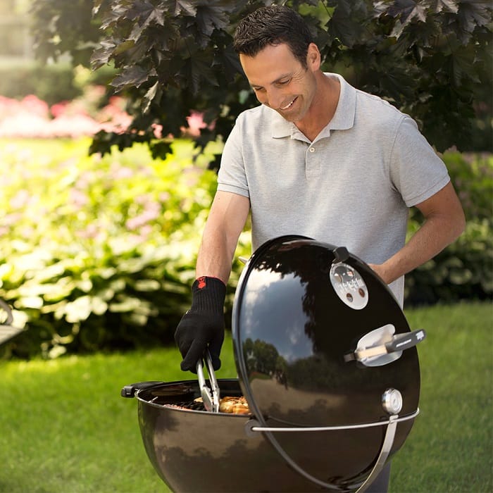 Man grilling on Weber Master Touch charcoal grill in black