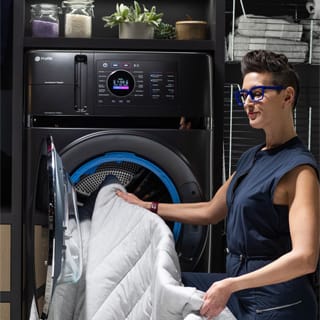 A woman pulls a duvet out of the combo washer and dryer and examines it.