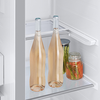 Image inside of fridge showing contents including two tall wine bottles.