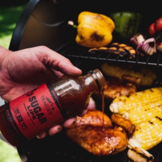 Traeger Sugar Lips BBQ Glaze is poured on a grilled chicken breast.