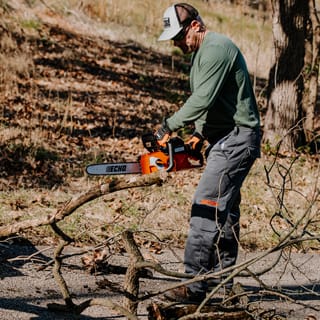 Man cutting tree branches with ECHO chainsaw
