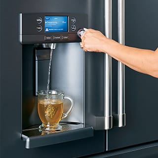 A woman dispenses hot water from her refrigerator.