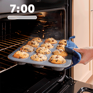 Side view of chocolate chip muffins being pulled out of the oven.