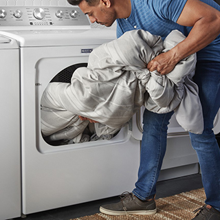 A person removing the blanket from washer after the wash and dry cycle.