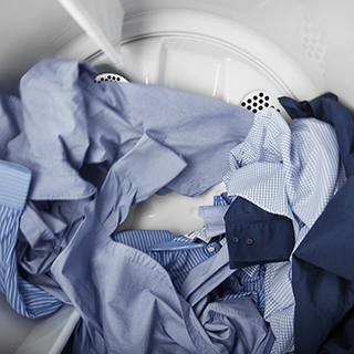 Clothes getting clean! Blue and white shirts in the washing machine.