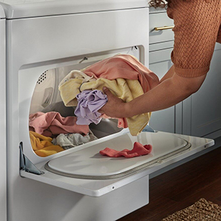 Person taking clothing out of a white Whirlpool Dryer