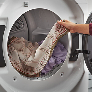 Person emptying clothing from a Whirlpool Dryer