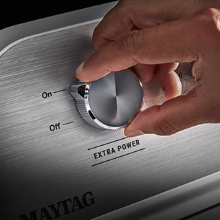 A person turning on a washer.